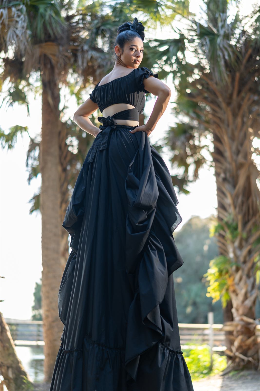Zanquera con vestido negro entre palmeras
